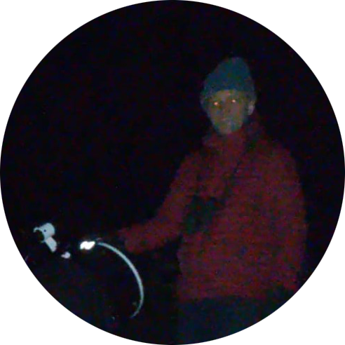 image of a man standing next to a telescope in the dark